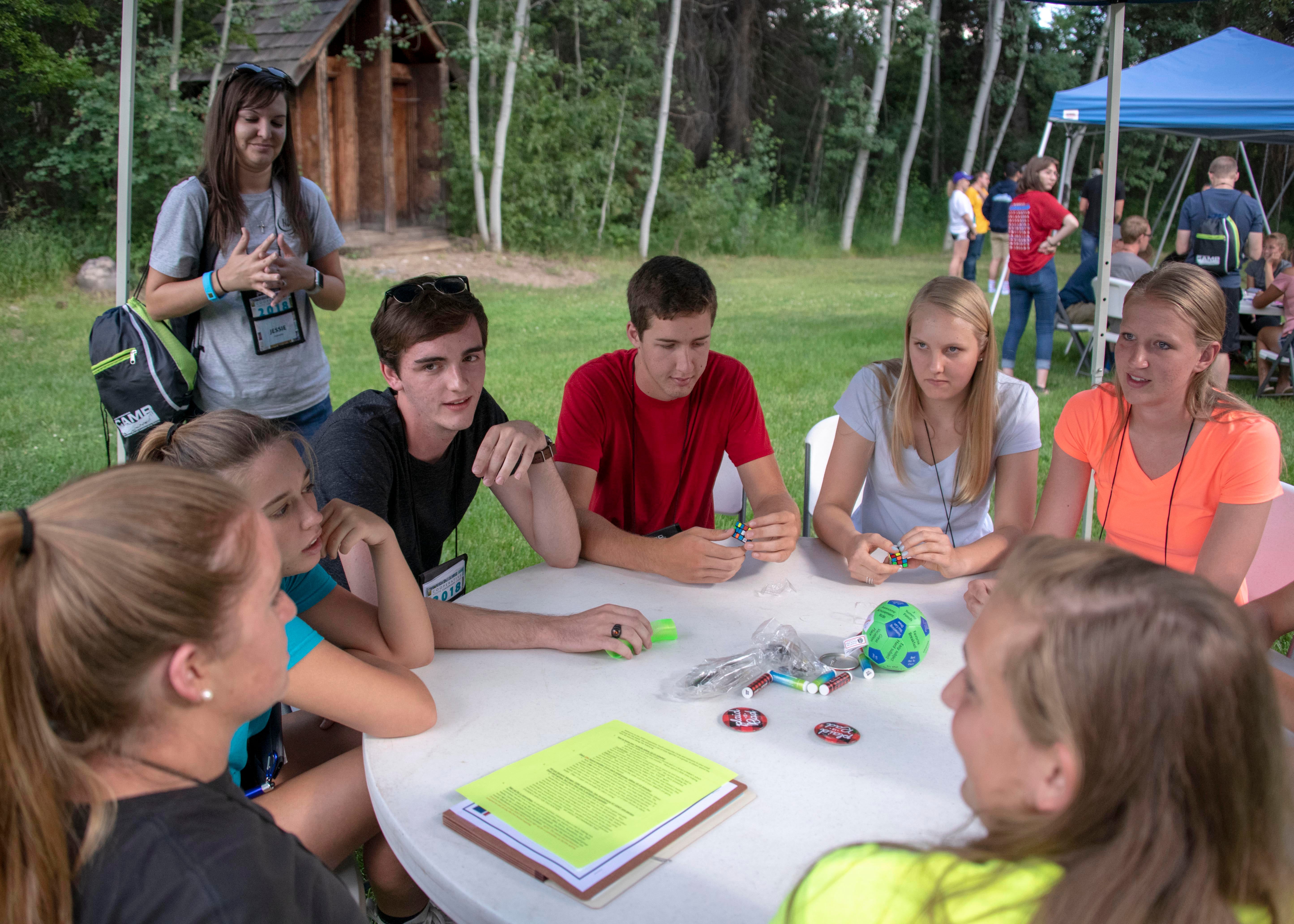 Campers sitting around a round table discussing their newly formed candy cooperative